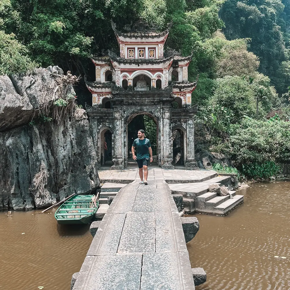 Homme sur un pont devant un temple vietnamien
